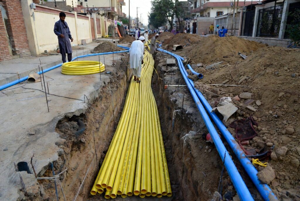 MDPE Pipes Uses: Gas, Water & Where They Apply 2 MDPE pipes laid in a trench during gas and water infrastructure installation on a Pakistani residential street with local workers handling yellow gas lines and blue water lines