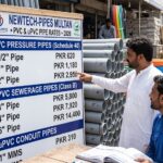 PVC pipe price list board displayed outside a wholesale hardware shop in Pakistan showing rates for pressure pipes, uPVC sewerage pipes, and conduit lines